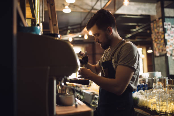 istock Young male barista preparing drink at coffee machine 691460564