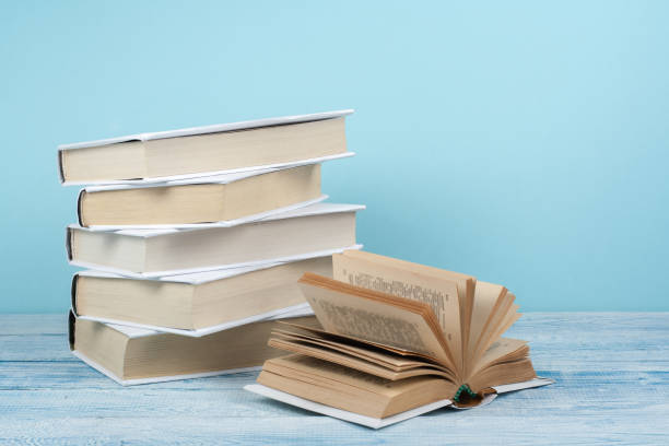istock Book stacking. Open book, hardback books on wooden table and blue background. Back to school. Copy space for text 691467280