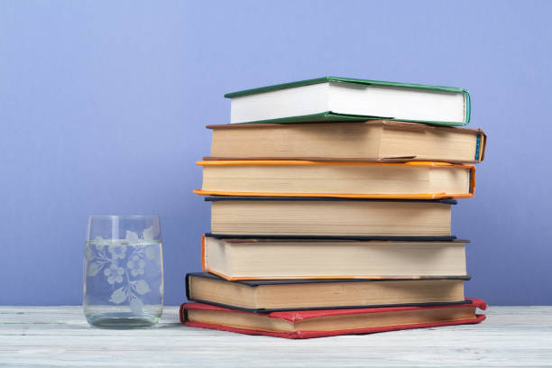 istock Book stacking. Open book, hardback books on wooden table and blue background. Back to school. Copy space for text 691467322