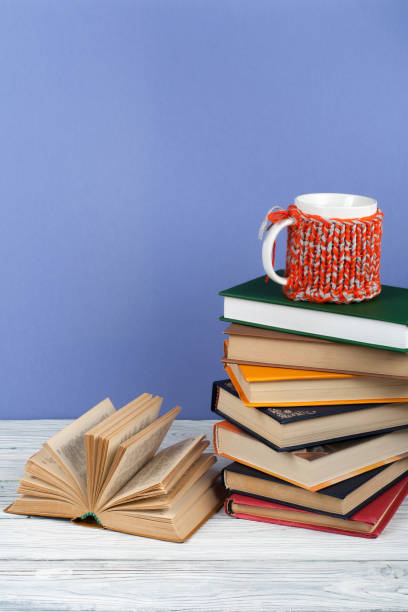 istock Book stacking. Open book, hardback books on wooden table and blue background. Back to school. Copy space for text 691467354
