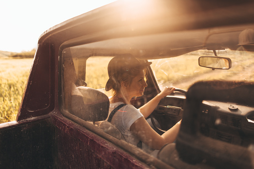 Photo of young woman who has chosen life on farm as her lifestyle - riding a pick-up truck while doing errands