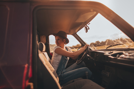 Photo of young woman who has chosen life on farm as her lifestyle - riding a pick-up truck while doing errands