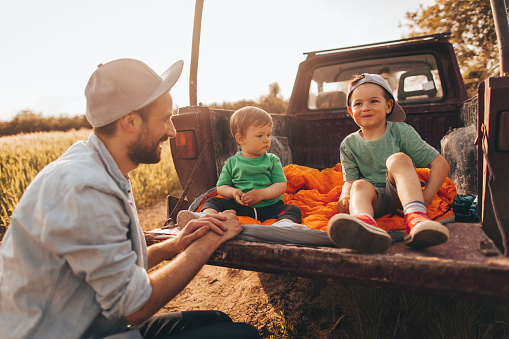 Photo of young father bonding with his boys by taking the outdoors in the nature with a family pick up truck