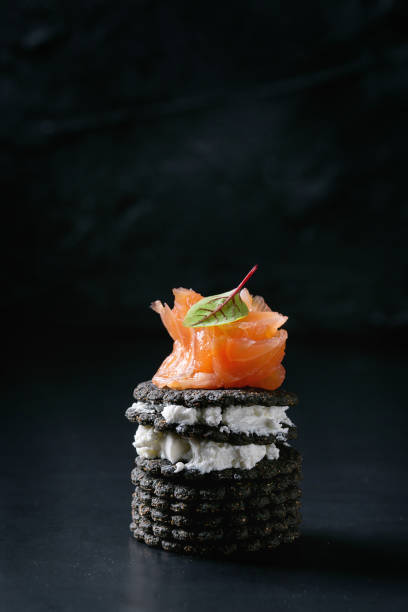 черные крекеры с лососем и ягодами - appetizer salmon smoked salmon cracker стоковые фото и изображения