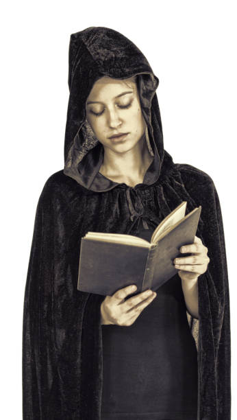 istock Hooded widow in black robe reading book cross-processed 691490284