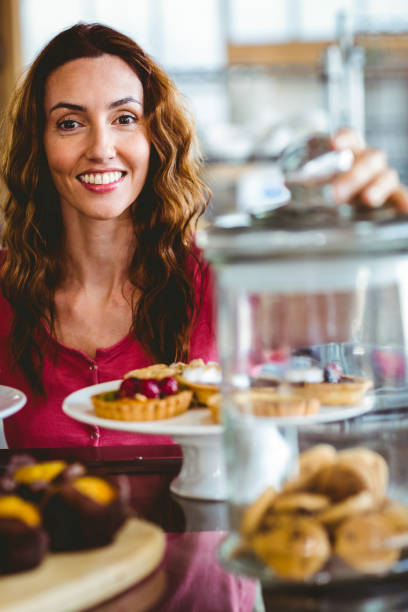 istock Pretty brunette smiling at camera behind plates of pastries 691490614