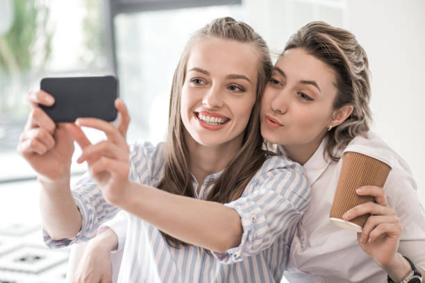 istock young smiling girlfriends taking selfie on smartphone at cafe 691492748