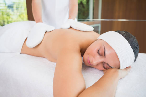 istock Beauty therapist rubbing womans back with heated mitts 691504172