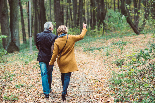 Mature couple walking in autumn park Back view of beautiful mature couple walking in autumn park racewalking photos stock pictures, royalty-free photos & images