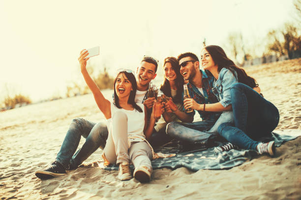 istock Happy young people having fun on the beach drinking beer and doing selfie 691504688