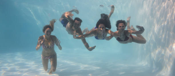 istock Smiling friends looking at camera underwater in swimming pool 691506884