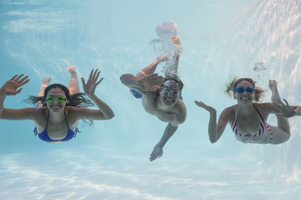 istock Smiling friends looking at camera underwater in swimming pool 691506992