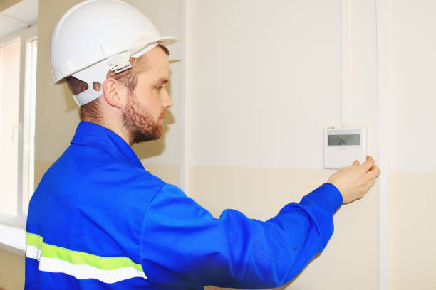 istock engineer in the white helmet sets the temperature on the control panel of the air conditioner 691519116