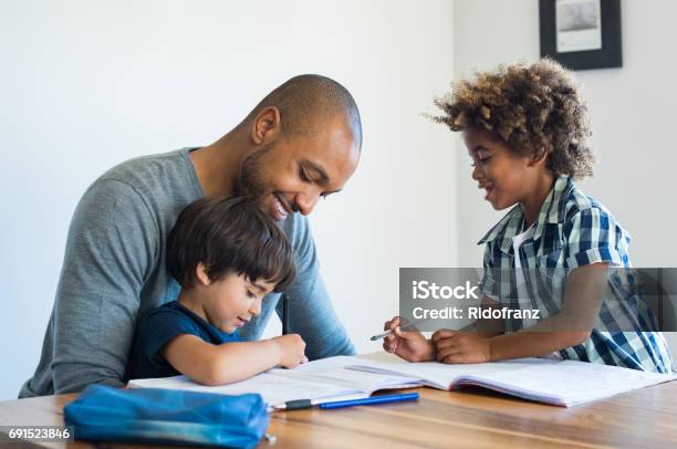 Padre Ayudando A Sus Hijos Con La Tarea Foto de stock y más banco de imágenes de Padre - Padre, Aprender, Deberes