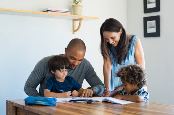 Parents helping children with homework Multiethnic parents helping children with their homework at home. Young father and mother helping sons study at living room. Little boys completing their exercises with the help of dad and mom. homework stock pictures, royalty-free photos & images