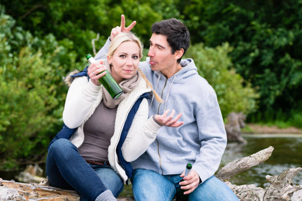istock Lovers in vacation sitting at waterside clinking beer bottles 691523920
