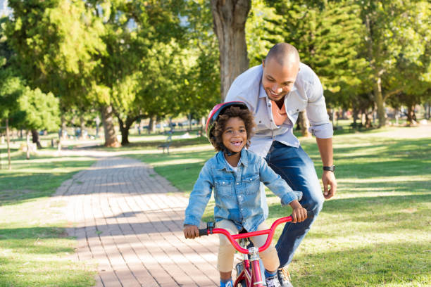 отец учит сына езде на велосипеде - park and ride стоковые фото и изображения