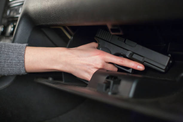 la mano de la mujer saca una pistola de la guantera en el coche. - guantera fotografías e imágenes de stock