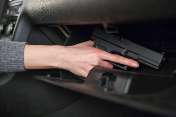 The female hand pulls out a gun from the glove box in the car. The female hand pulls out a gun from the glove box in the car glove box stock pictures, royalty-free photos & images