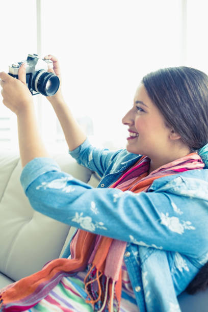 istock Smiling brunette sitting on sofa taking a selfie 691538160