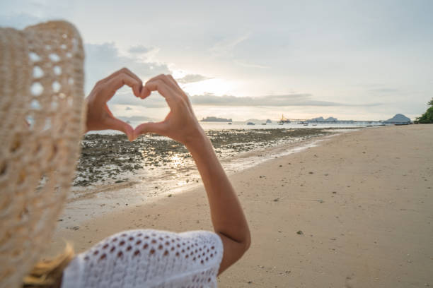 istock Woman making heart shape frame on tropical beach landscape 691544046