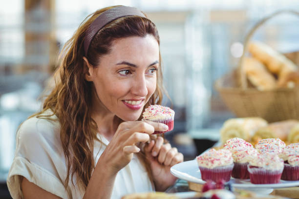 istock Pretty brunette holding and smelling cupcake 691544164