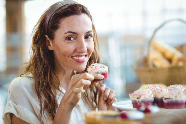 istock Pretty brunette looking at camera and holding cupcake 691544182