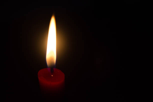 istock Red candle with yellow flame on black background 691551838