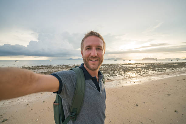 istock Selfie of young man on beach at sunset 691554760