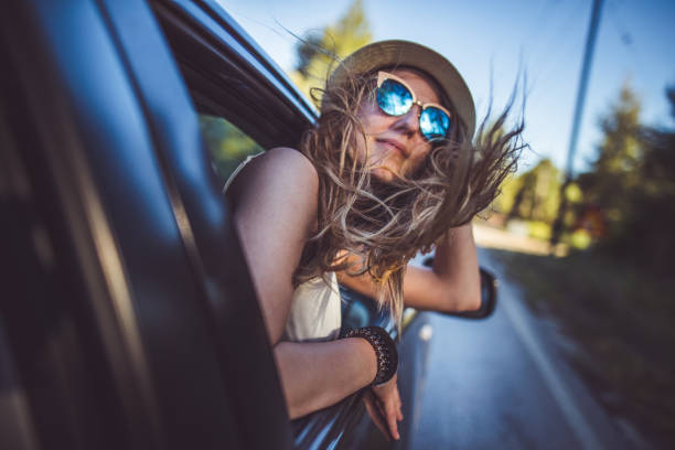 Girl having fun on the road trip Young hipster woman leaning on the car window while driving and having fun hipster car stock pictures, royalty-free photos & images
