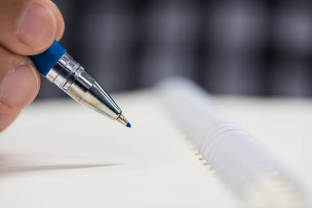 istock man's hand holding a pen to writing on paper 691566186