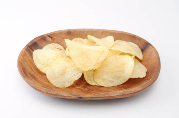 istock potato chips on wood plate on white background 691573054