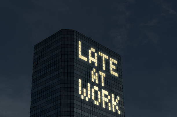 istock Late at work concept. Working overtime and extra hours. Tired and stressed from too much things to do at job. Text made by office building window lights at night. 691579874
