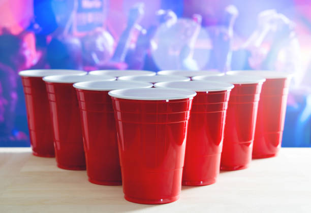 расположение турнира по пивной понгу. много красных кубков партии в ночном клубе, полном людей, танцующих на танцполе в фоновом режиме. идеа - disposable cup red beer plastic стоковые фото и изображения