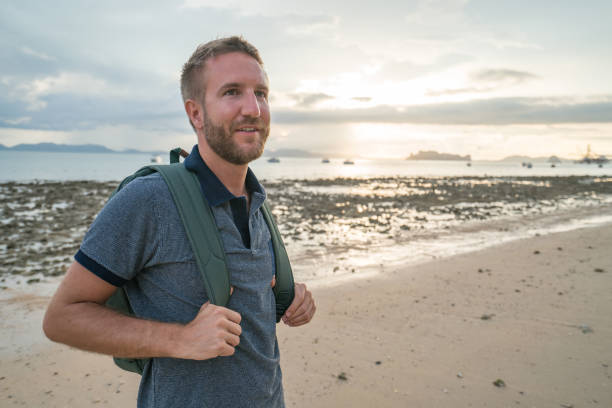 istock Young man on tropical beach contemplating sunset 691595426