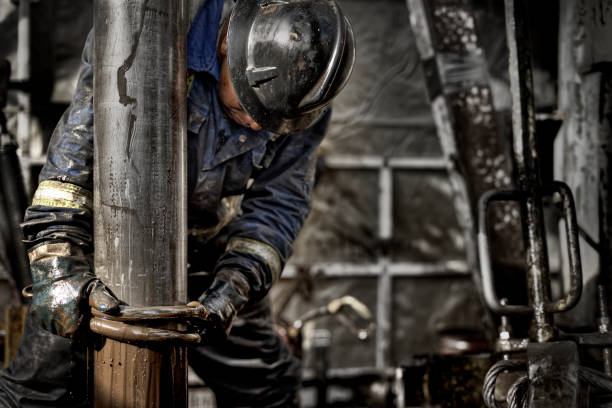 Oil Rig Worker 1.0 Oil Rig Worker wearing his safety gear working on the muddy drill floor drilling rig stock pictures, royalty-free photos & images