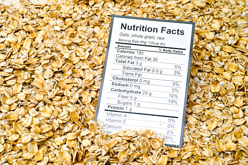 Nutrition facts of whole grain raw oats with oats background.