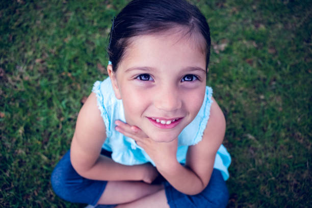 Upward view of a smiling little girl in the park on a sunny day