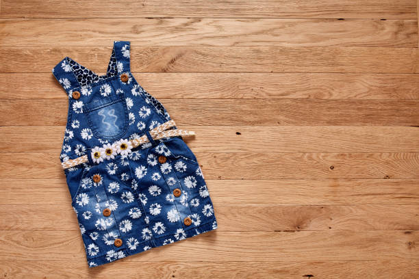 istock Cute denim dress on wooden background. 691610020
