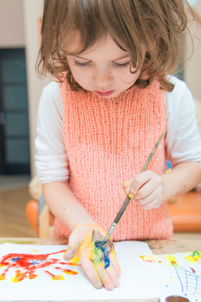 istock girl drawing paints on paper and hands 691615928