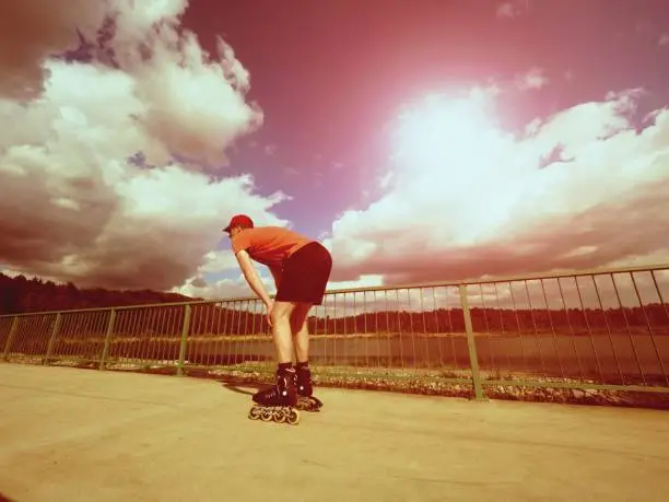 Vintage tone filter effect color style. Sportsman  with inline skates ride in summer park close to handrail, outdoor roller skater on park bridge