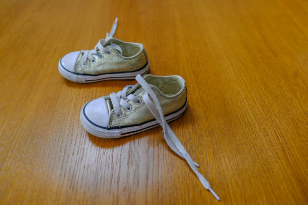 Small child's canvas shoes on an oak floor with trailling laces.