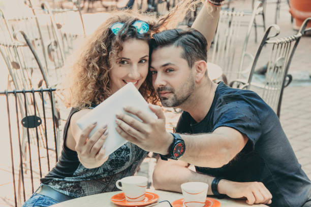 istock Dating. Young couple drinking coffee in the cafe and having fun with tablet 691648852