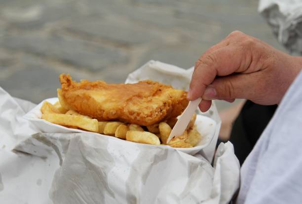 istock man eating fish and chips takeaway in paper 691673246