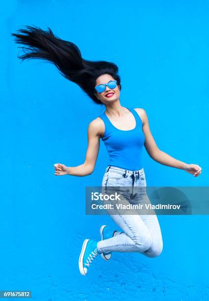 Jumping Young Woman Stock Photo - Download Image Now - Blue Background, Women, Blue