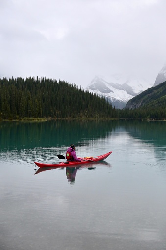 A woman paddles out in incredibly beautiful conditions on Maligne Lake at dawn.
