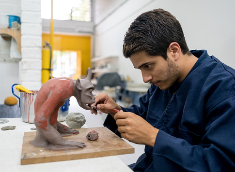 Portrait of a design student at the university in a pottery class - education concepts