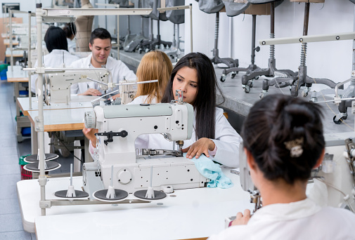 Group of Latin American students at a fashion school sewing on machines - fashion concepts
