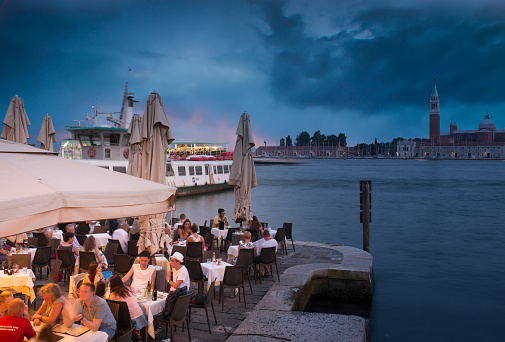 Venice, Italy - July 23, 2015: Venetian dining, seen from the academica bridge, see people sitting in a small restaurant oudside and enjoing the night