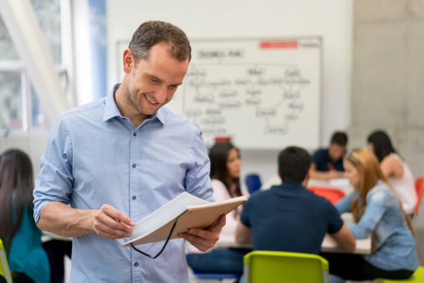 istock Happy teacher reading notes in class at the university 691703520